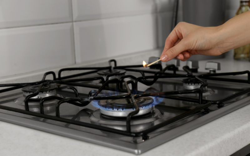 woman lighting gas stove with match